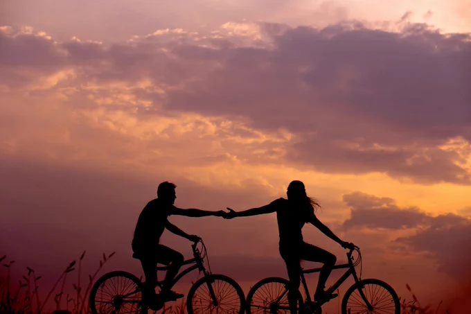 A couple on bicycles holding hands. Photo by Everton Vila on Unsplash
