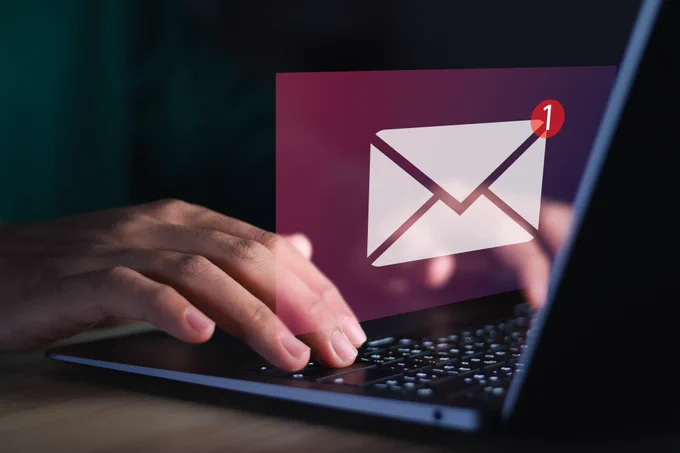 Hands typing on a laptop keyboard with a new email