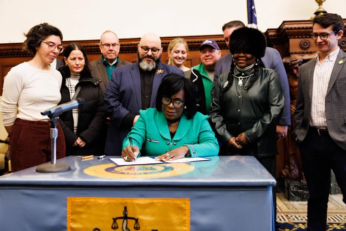 Mayor Cherelle L. Parker sitting at a desk, signing a bill into law.