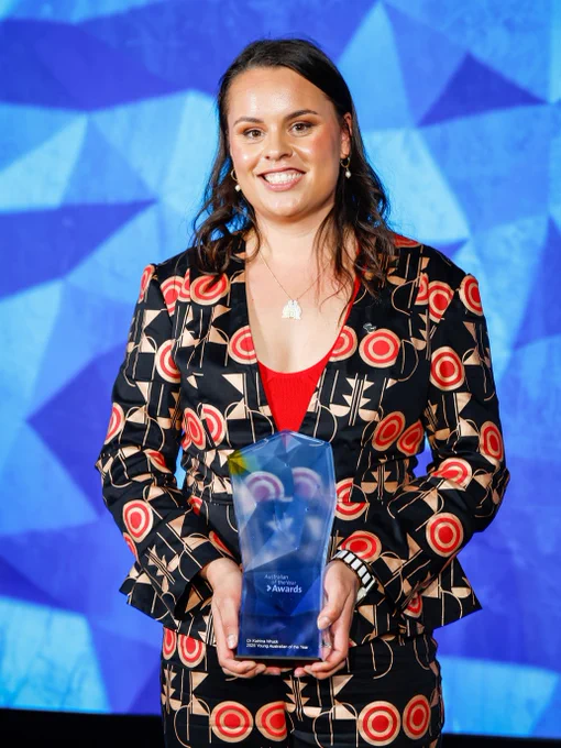 Young Indigenous woman holding the Young Australian of the Year Award and smiling for the camera.