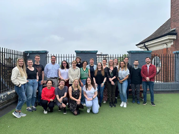 21 members of Dogs Trust's Research team pose for a photo outdoors. Lots of smiling faces.