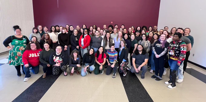 Group photo of MOCSA staff standing in front of a maroon wall.