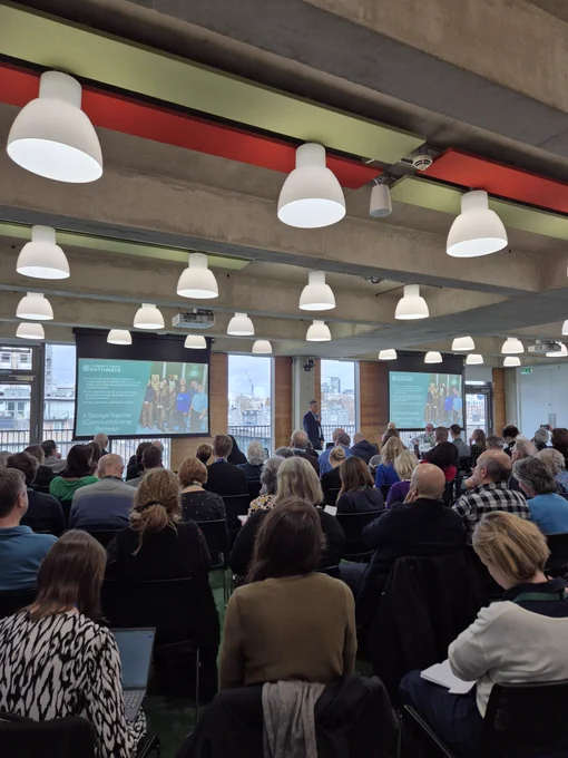Room full of seated people with their backs to the camera. 