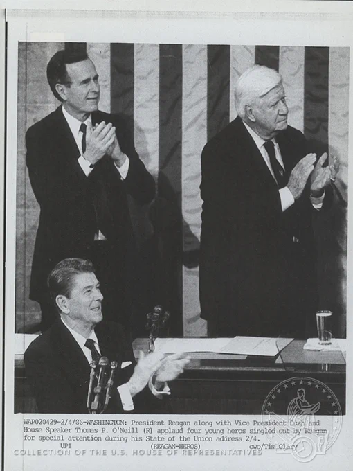 President Reagan, Vice President Bush, and Speaker O'Neill on the Rostrum in the House Chamber applauding toward the gallery
