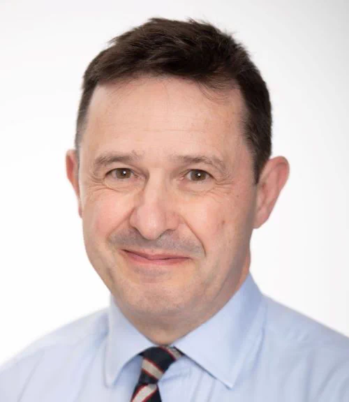 Head shot image of Professor David Barron. He is wearing a blue shirt with a striped tie and is smiling.