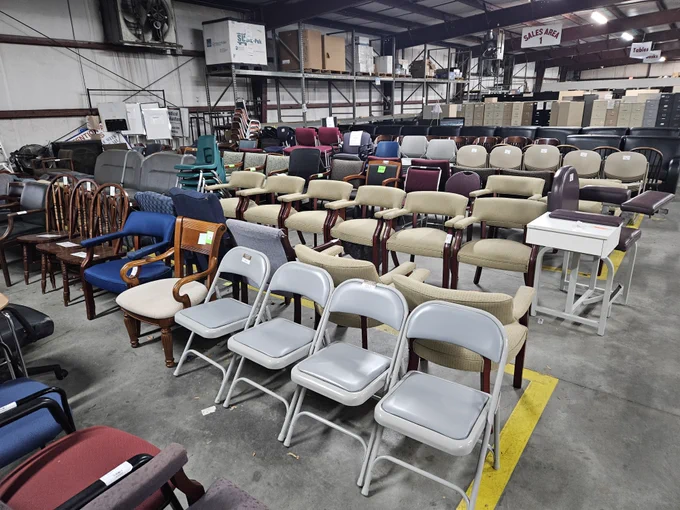 An assortment of various chairs and furniture items displayed in a large indoor warehouse setting.