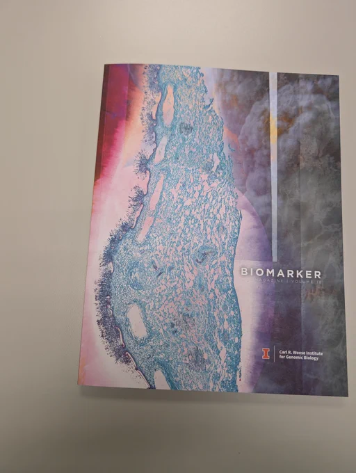 The front cover of a magazine showing a cell. The words Biomarker Magazine Volume 18 appear in the middle left of the cover. Carl R. Woese Institute for Genomic Biology appears in the bottom right.