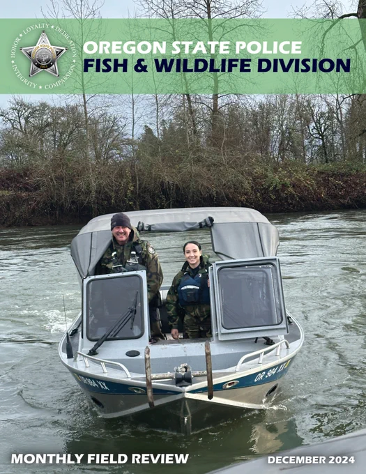 Two OSP Fish and Wildlife Troopers stand on a patrol boat on a river with trees in the background.