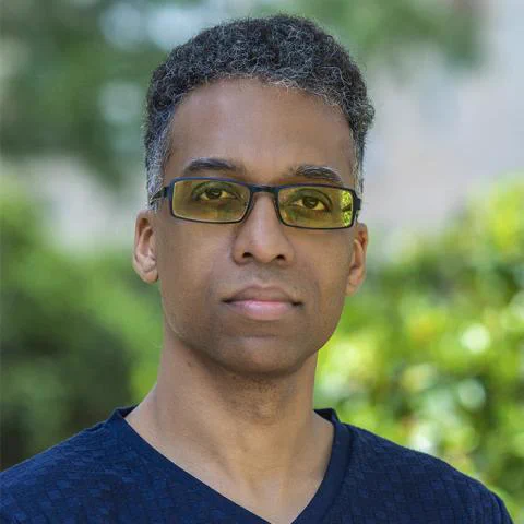 Photo of Alvin Grissom looking seriously at the camera with greenery in the background.
