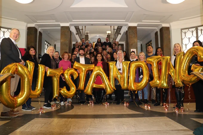 group of AfC and Kingston Council employees holding up balloons that read outstanding 