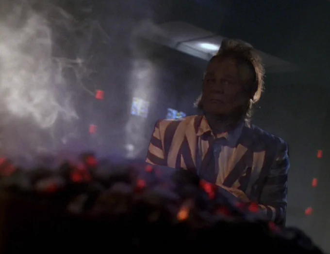 Neelix in the episode Barge of the Dead. In front of him is a smoldering pile of rocks, coals perhaps. He is wearing Beetlejuice's suit.