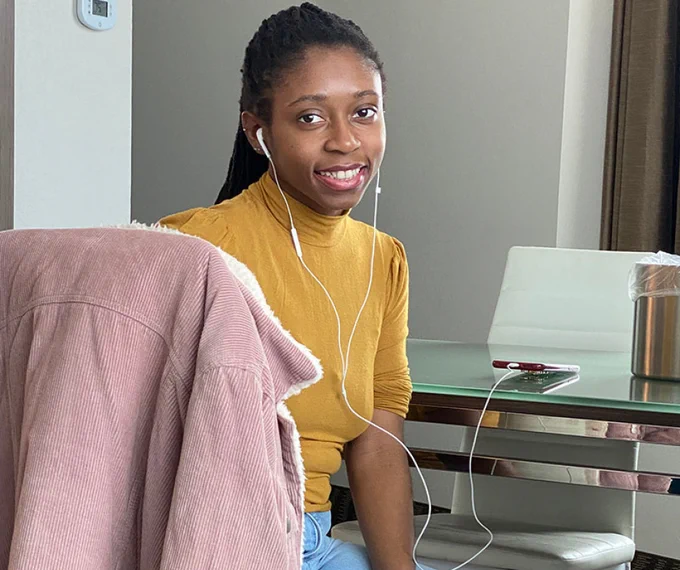 Adrienne sitting in a chair at a desk, smiling at the camera. 