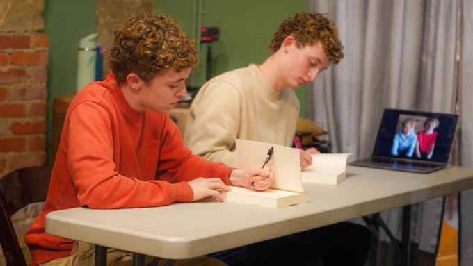 Cody (left) and Taylor (right) sign copies of the published book at the end of the event.
