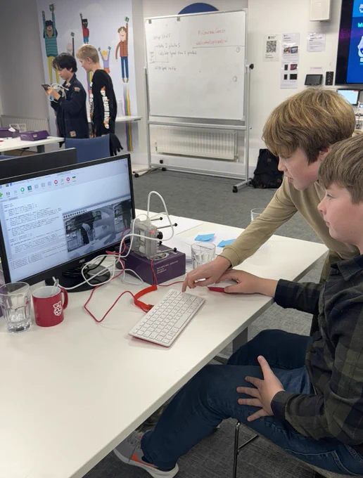 Two young creators helping each other to do Astro Pi Mission Space Lab. One is touching the mouse, the other the keyboard. They have an Astro Pi computer in front of them