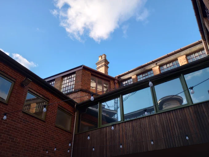Looking up at an old building with brick wall, wooden cladding and windows