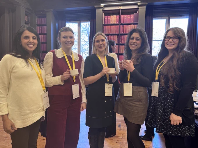 A group of five women smile for a photo, in the RCS England library. 