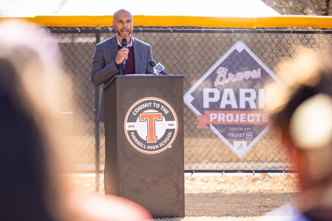 Truist representative speaks from podium at the ceremonial ribbon-cutting of the Braves Park Project at Therrell High School