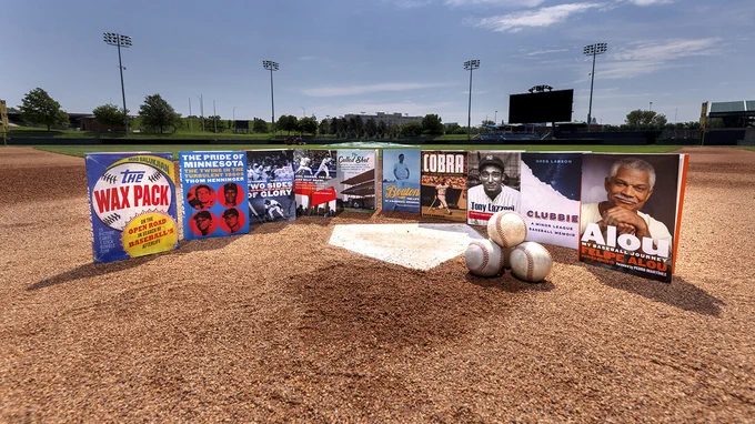 Ten books about baseball — all from the University of Nebraska Press — are lined up in front of home plate at a baseball stadium. (Craig Chandler/University Communication and Marketing)