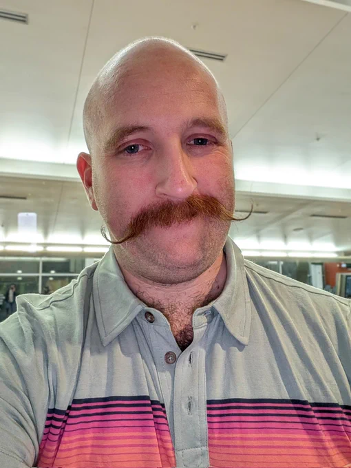 Selfie showing off a long, curly, handlebar mustache