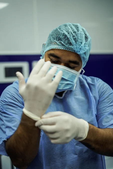 A surgeon puts on gloves