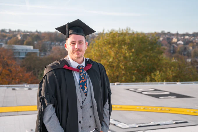 Jamie in graduation cap and gown on the helipad