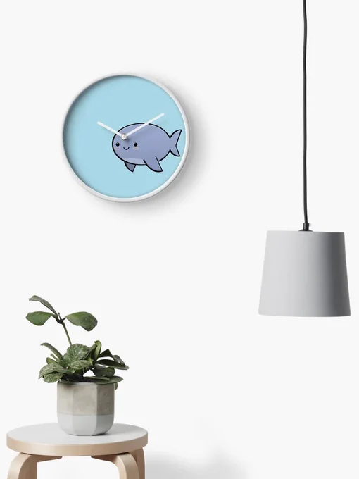 Picture of a white room with a plant, and a clock on the wall. The clock is marking 10:10, and the face of the clock is a cartoon of a narwhal. The place where the tusk would go is the opening for the clock hands.
