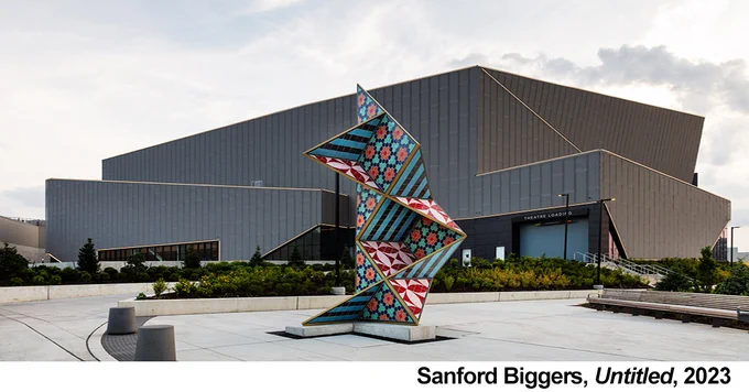 Image showing a large vertical angular sculpture with mosaic tile patterns located on a plaza.