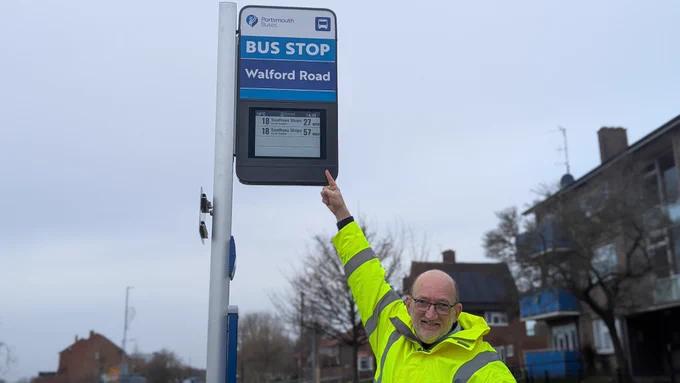 Cllr Candlish, Cabinet Member for Transport pointing at a newly installed pole mounted bus stop sign at Walford Road in Portsmouth. 