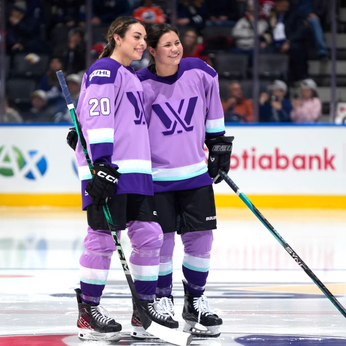 Sarah Nurse and Abby Roque smile for a photo on ice while wearing purple PWHL uniforms.
