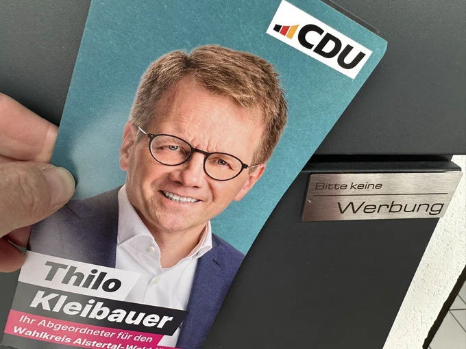 Werbeflyer des Abgeordneten Thilo Kleibauer vor einem Briefkasten mit „Bitte keine Werbung“ Schild.