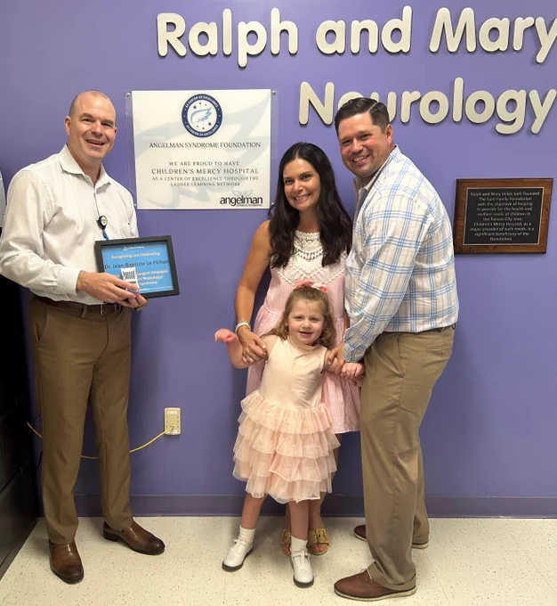 The Sargent family (Laura, Patrick, and their daughter Maddie) stand next to Dr. J. B. Le Pichon. all are smiling. Dr. Le Pichon holds a framed certificate recognizing him as the recipient of the Madison Lauren Sargent Endowed Professorship in Neurology/Angelman Syndrome