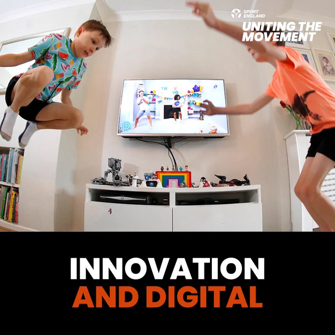 Two children energetically jumping in a living room while playing a video game displayed on a large TV screen,with the words Innovation and digital. The Sport England logo features in the top right.