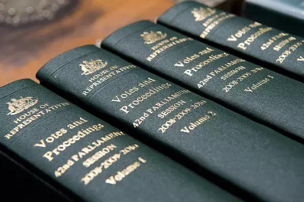 Four bound hansard proceedings on a wood desk