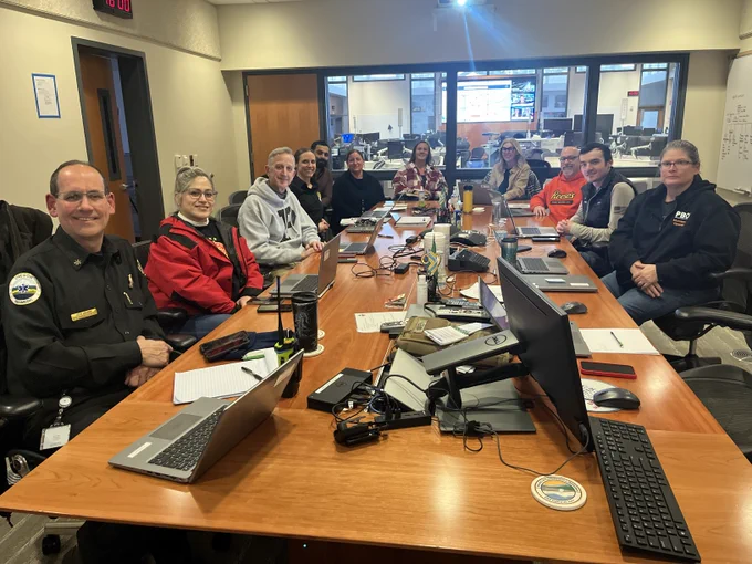 Mayor Keith Wilson is in the company of other City of Portland employees, seated at a conference room table. Everybody is smiling at the camera. 