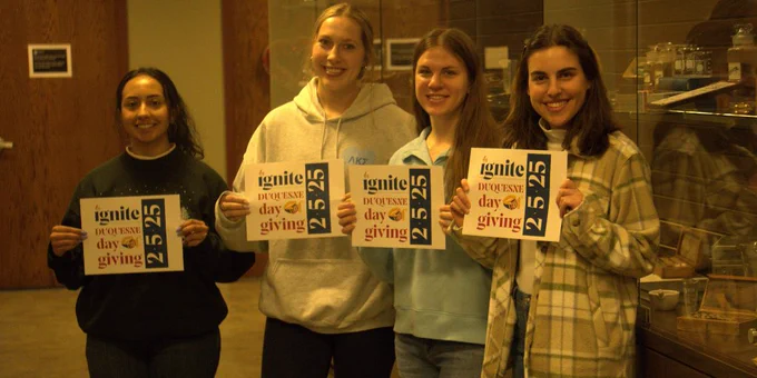 Students holding Duquesne Day of Giving signs.