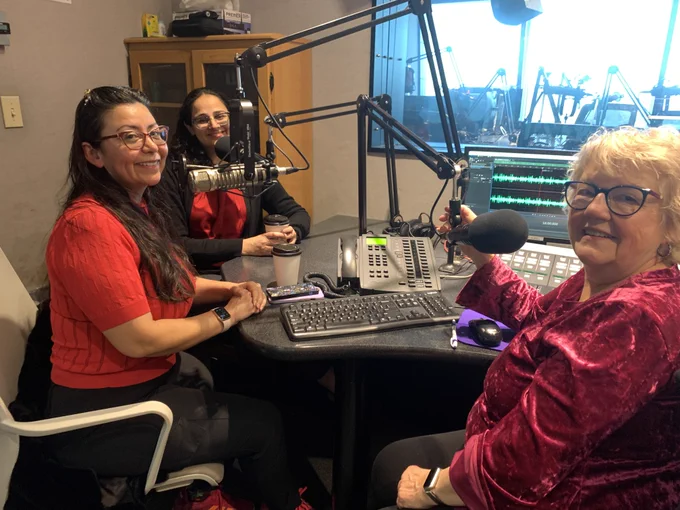 Cynthia and Dr. Kapoor in the studio with host, Kate Daniels. They pose for a photo in front of the mics after the interview finishes.