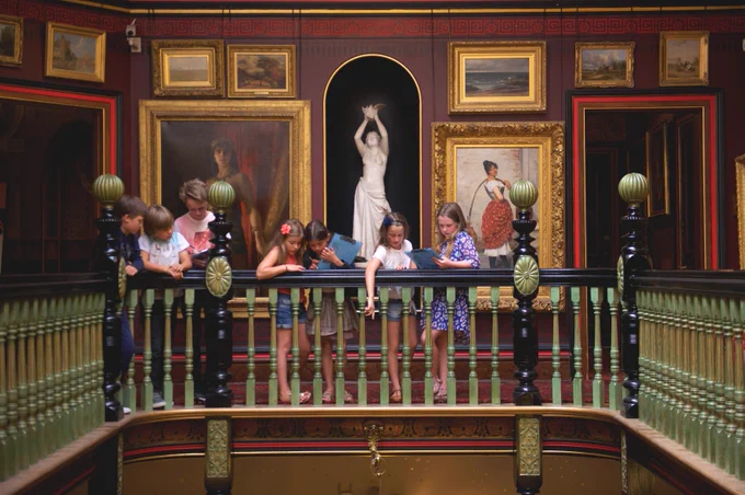 Group of children on a balcony with artwork in the background