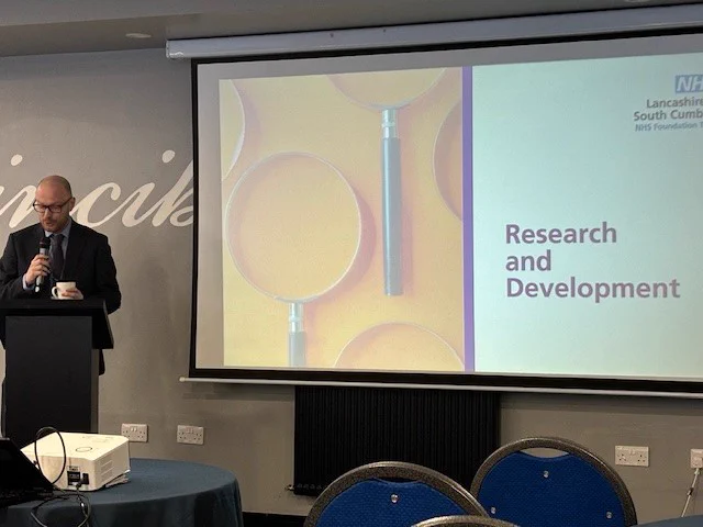Dr Gareth Thomas stands and addresses the Conference