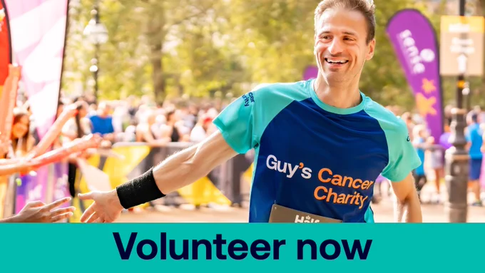 A Guy's Cancer Charity runner smiling at supporters along the side-line.  