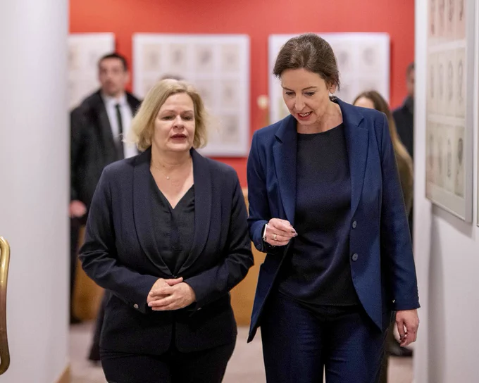 Ministerinnen Faeser und Uitermark gehen einen Flur entlang und sprechen miteinander.