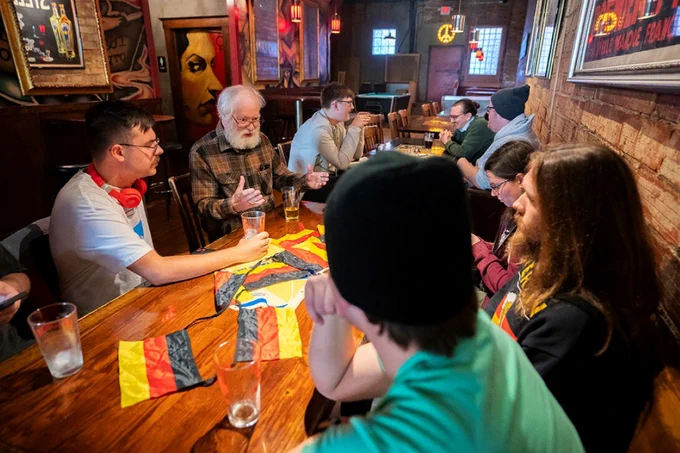 Students talking with a professor around a table at a restaurant. 