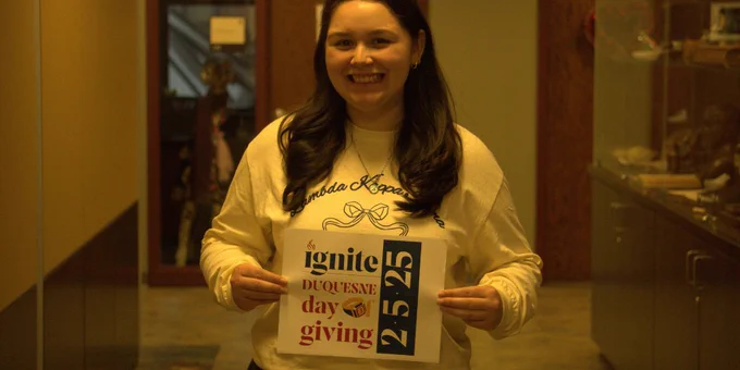 Student holding Duquesne Day of Giving sign.