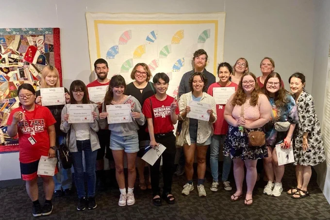 students holding up pieces of paper for a group photo.
