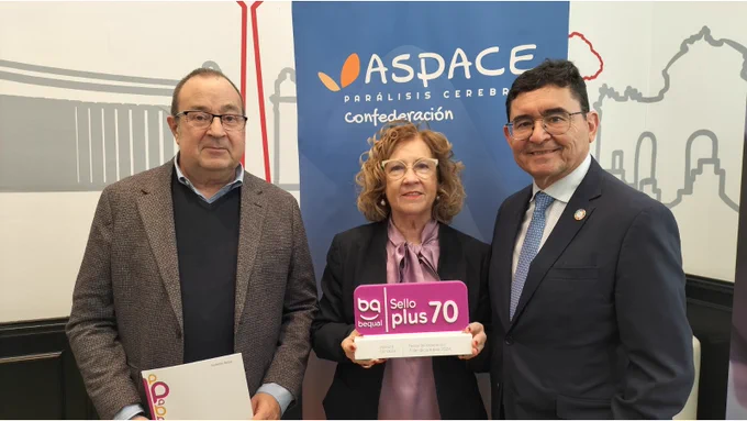 Imagen donde se ve a tres personas, dos hombres y una mujer. L mujer tiene una placa en la mano que pone sello plus 70 de color blanco y rosa. Detrás aparece un cartel con el logotipo de Confederación ASPACE.