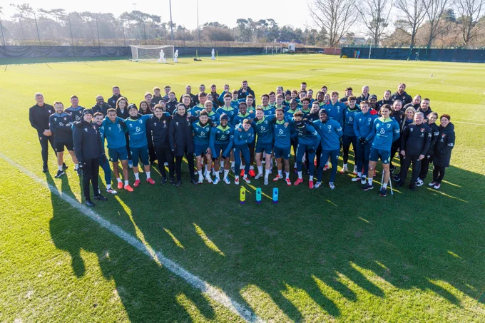 The entire first-team staff pose with all three Premier League trophies.