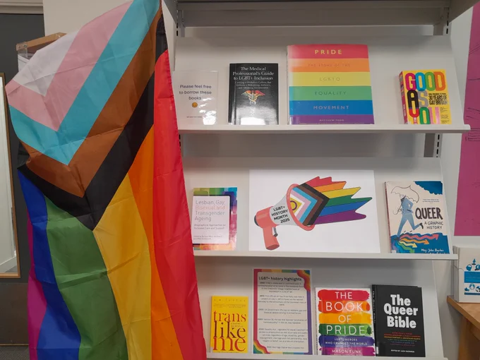 A photo of an NHS library display of LGBT  books, accompanied by a PRIDE flag. 