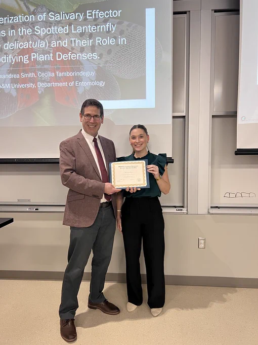 Phillip Kaufman, Ph.D., Department Head of Entomology and Professor stands next to Master's student, Alexandrea Smith for a photo presenting her with an award. 