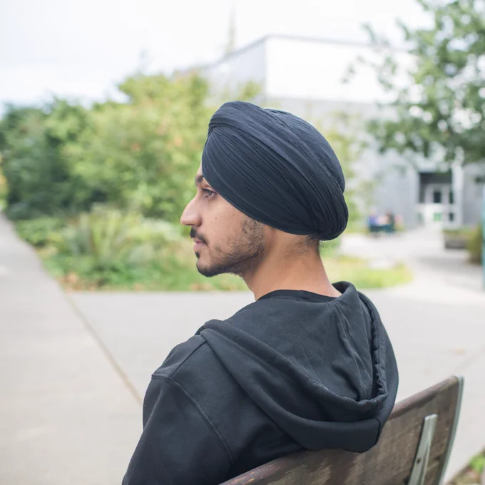 A man sits on a bench outside and looks outward.