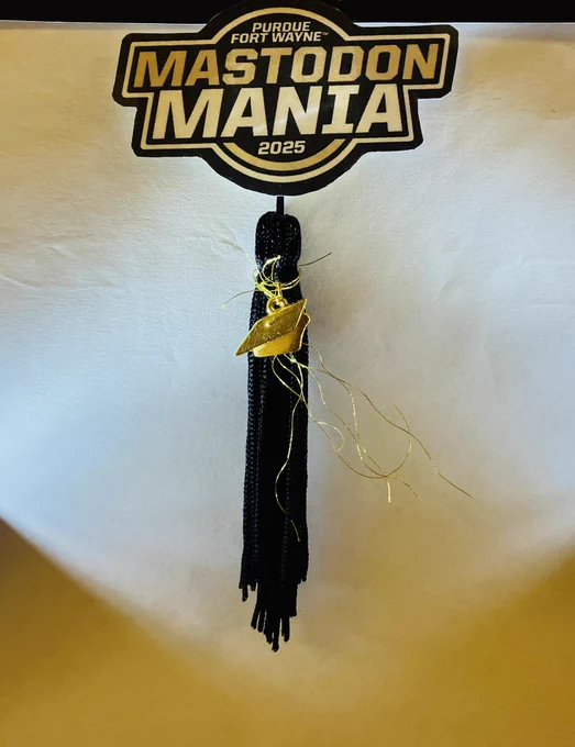 Mastodon Mania logo, black graduation tassle with a gold graduation cap