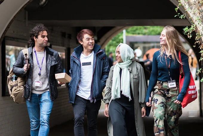 Four students walking through a tunnel. They are smiling together. James Tye for UCL.